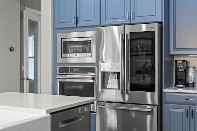 3865 W Stillwood Ln, Lake Mary, FL 32746 - kitchen featuring appliances with stainless steel finishes, blue cabinetry, light countertops, and decorative backsplash
