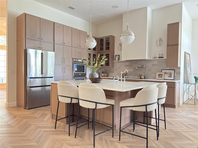 1266 Saint Albans Loop, Lake Mary, FL 32746 - kitchen with appliances with stainless steel finishes, a kitchen island with sink, light countertops, a breakfast bar area, and a textured ceiling