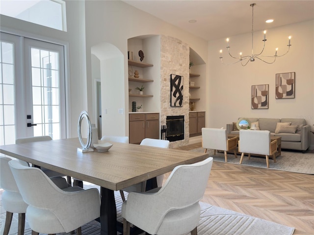 1266 Saint Albans Loop, Lake Mary, FL 32746 - dining area featuring built in features, a chandelier, a stone fireplace, arched walkways, and a high ceiling