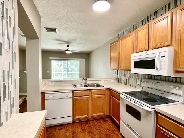 kitchen with white appliances, a sink, ceiling fan, light countertops, and dark wood-type flooring