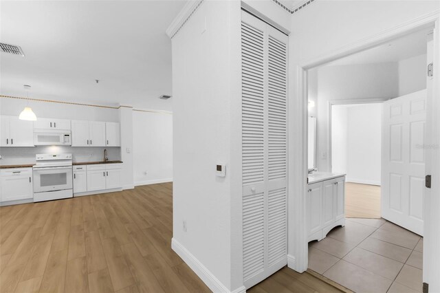 3561 Conroy Rd Unit 216, Orlando, FL 32839 - hall featuring light wood finished floors, baseboards, and a sink
