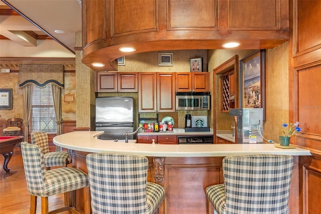 3561 Conroy Rd Unit 216, Orlando, FL 32839 - kitchen featuring stainless steel appliances, light countertops, a breakfast bar area, brown cabinets, and light wood finished floors