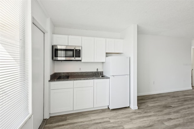 935 S Atlantic Ave Unit 302, Daytona Beach, FL 32118 - kitchen featuring stainless steel microwave, freestanding refrigerator, a sink, white cabinetry, and a textured ceiling