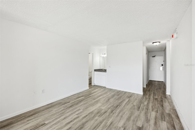 935 S Atlantic Ave Unit 302, Daytona Beach, FL 32118 - unfurnished living room featuring light wood-type flooring, a textured ceiling, and baseboards