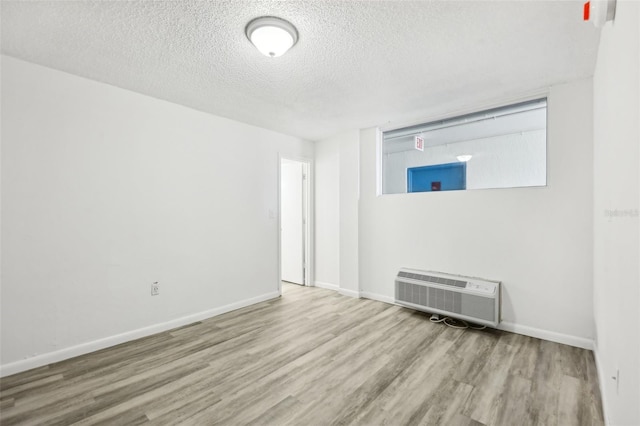 935 S Atlantic Ave Unit 302, Daytona Beach, FL 32118 - unfurnished room with wood finished floors, a textured ceiling, baseboards, and a wall mounted air conditioner