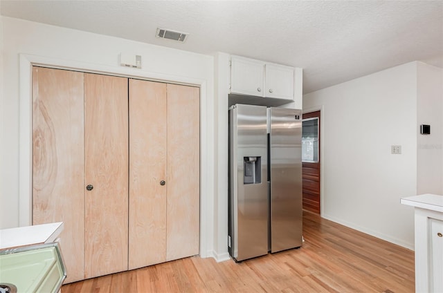 1322 Royal Birkdale Cir, Rockledge, FL 32955 - kitchen featuring stainless steel fridge with ice dispenser, light wood finished floors, baseboards, white cabinetry, and a textured ceiling