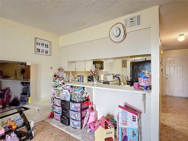 1806 Foxhall Cir Unit 1806, Kissimmee, FL 34741 - kitchen with tile patterned floors, a textured ceiling, and black microwave