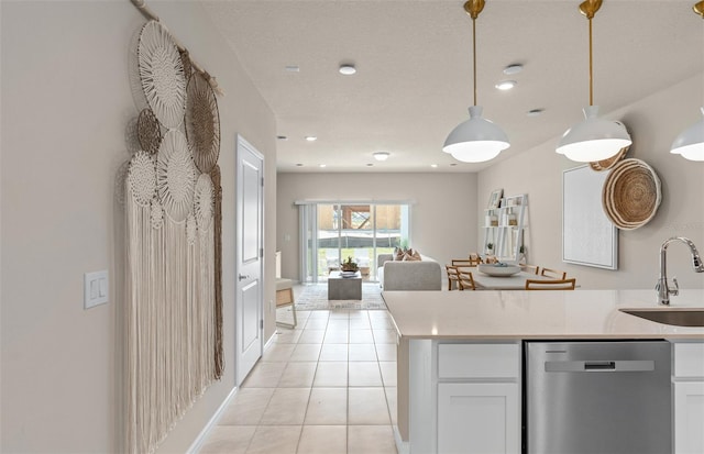 kitchen featuring stainless steel dishwasher, a sink, light tile patterned flooring, decorative light fixtures, and open floor plan