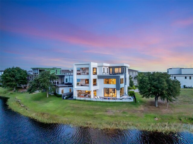 8157 Elion St, Orlando, FL 32827 - back of property at dusk featuring a water view, stucco siding, and a lawn