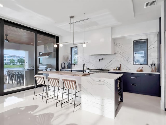 8157 Elion St, Orlando, FL 32827 - kitchen featuring modern cabinets, wall chimney exhaust hood, a kitchen bar, light stone countertops, and a center island with sink