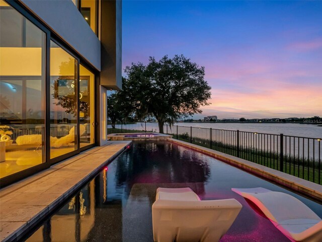 8157 Elion St, Orlando, FL 32827 - view of swimming pool featuring a pool with connected hot tub, a water view, and a fenced backyard