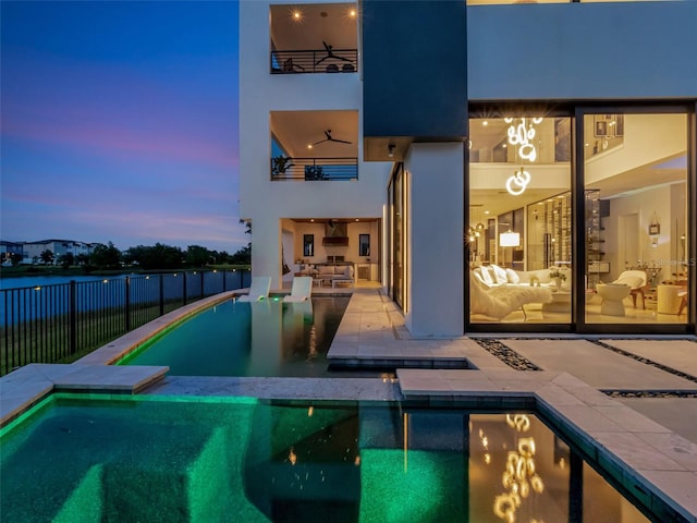 8157 Elion St, Orlando, FL 32827 - back of property at dusk with fence, a pool with connected hot tub, a patio area, and stucco siding