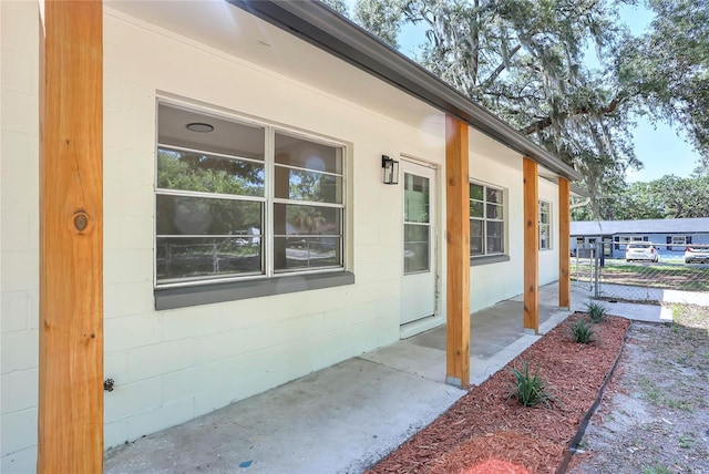 view of exterior entry with concrete block siding and a porch