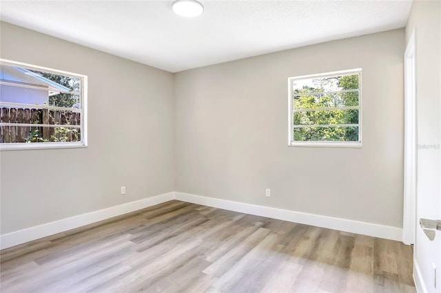 empty room featuring wood finished floors, baseboards, and plenty of natural light