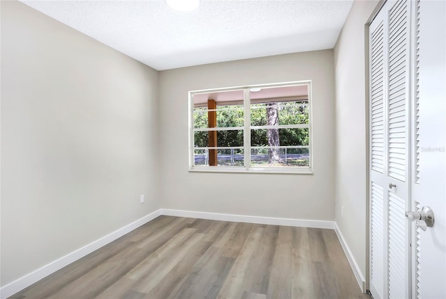 unfurnished bedroom featuring wood finished floors, a closet, and baseboards