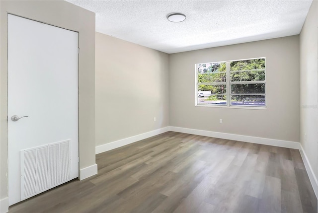 spare room with wood finished floors, a textured ceiling, and baseboards