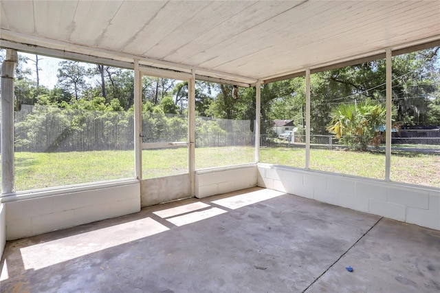 unfurnished sunroom featuring healthy amount of natural light and view of scattered trees