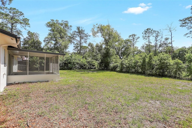 view of grassy yard with a sunroom