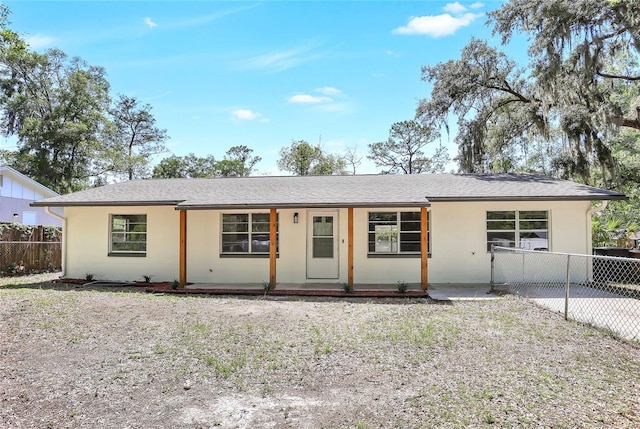 ranch-style house with fence, a porch, stucco siding, and roof with shingles