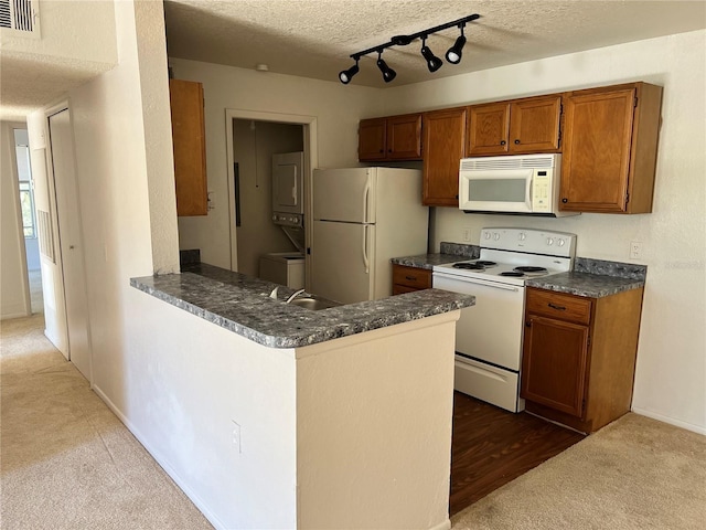 5291 Images Cir Unit 301, Kissimmee, FL 34746 - kitchen featuring white appliances, stacked washer and clothes dryer, carpet flooring, brown cabinetry, and dark countertops