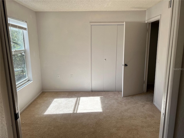 5291 Images Cir Unit 301, Kissimmee, FL 34746 - unfurnished bedroom featuring light colored carpet, multiple windows, a closet, and a textured ceiling