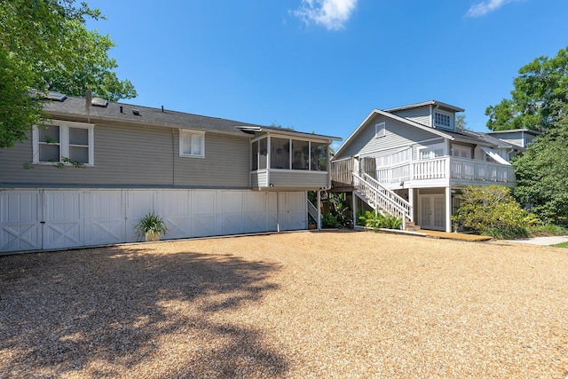 back of house featuring a sunroom, stairway, and a wooden deck