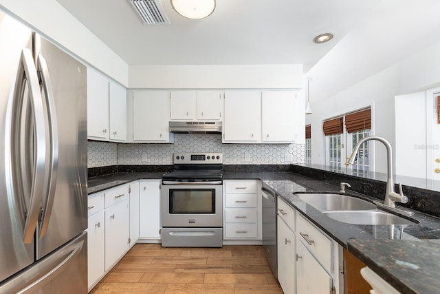 kitchen featuring appliances with stainless steel finishes, a sink, under cabinet range hood, backsplash, and white cabinetry