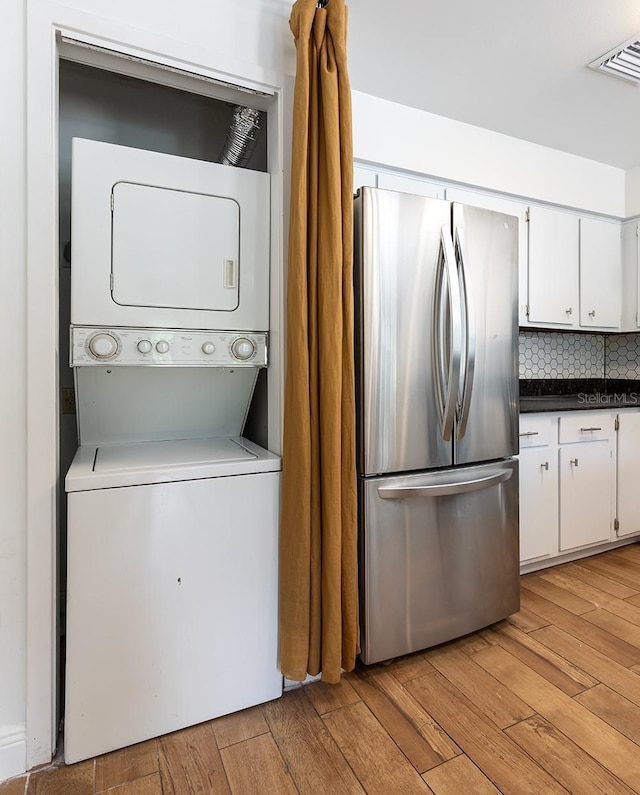 laundry area featuring estacked washer and dryer and light wood finished floors