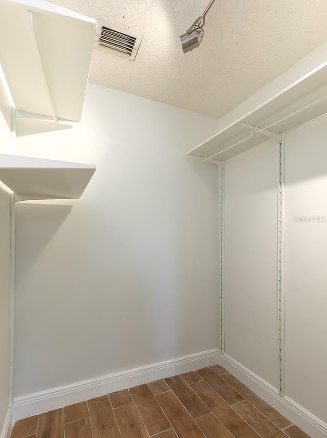 walk in closet with wood finish floors