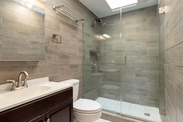 bathroom with toilet, a shower stall, vanity, and tile walls