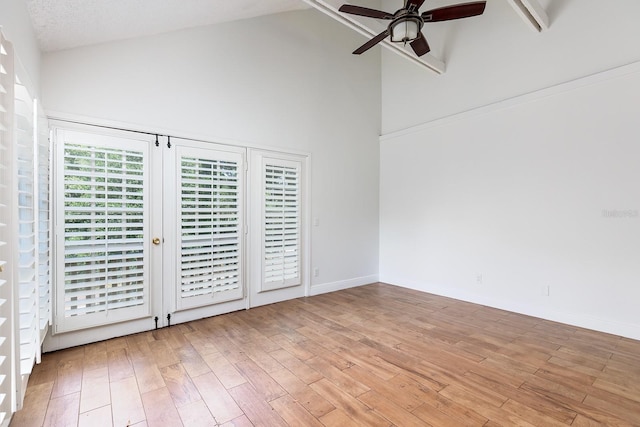 spare room with ceiling fan, high vaulted ceiling, and light wood-style floors