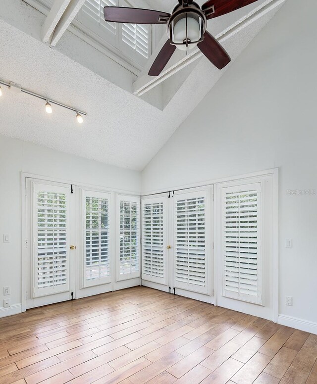 spare room with a ceiling fan, wood finished floors, high vaulted ceiling, beam ceiling, and french doors