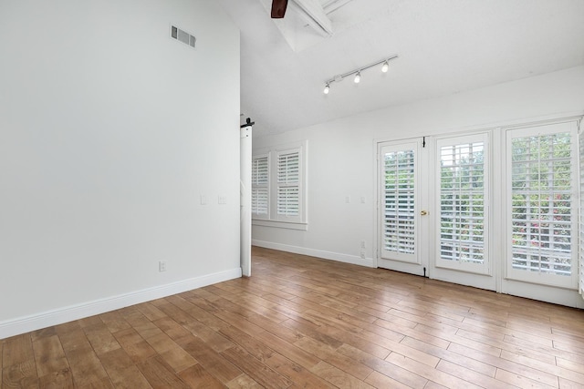 spare room featuring rail lighting, hardwood / wood-style floors, baseboards, lofted ceiling, and ceiling fan