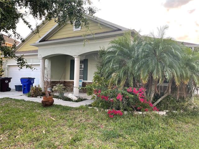 view of front facade featuring a porch, a garage, a front yard, stucco siding, and stone siding