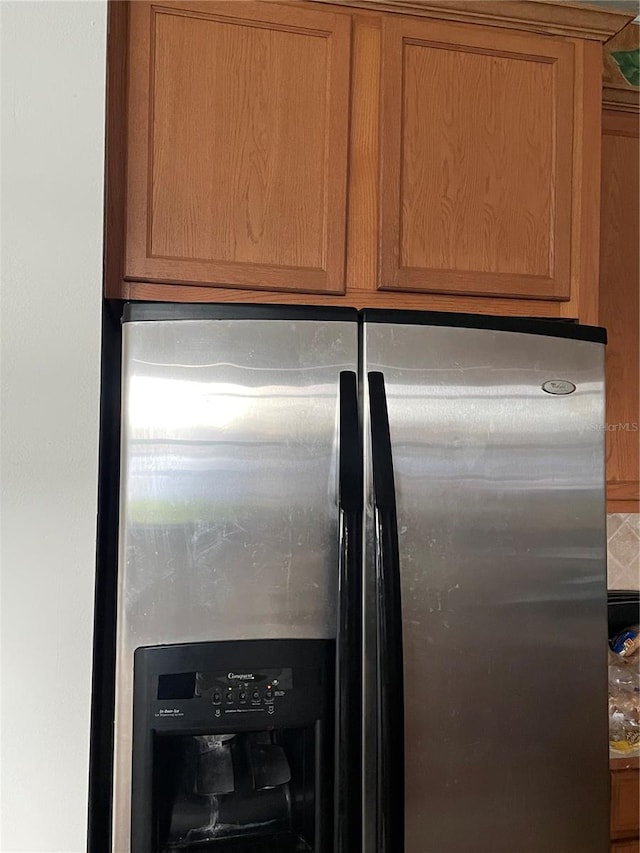 kitchen view of stainless steel fridge with ice dispenser and brown cabinetry