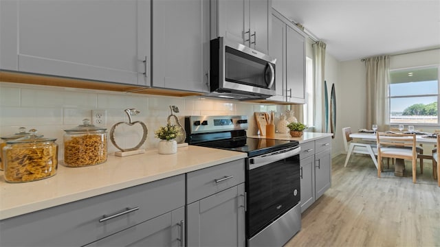 3326 Arch Ave, Ormond Beach, FL 32174 - kitchen featuring gray cabinetry, appliances with stainless steel finishes, tasteful backsplash, light wood-style floors, and light countertops