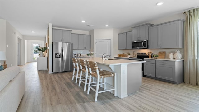 3326 Arch Ave, Ormond Beach, FL 32174 - kitchen with appliances with stainless steel finishes, gray cabinetry, a breakfast bar area, light wood-style floors, and recessed lighting