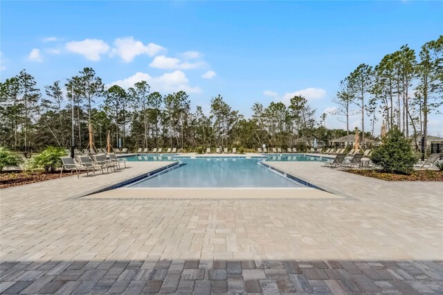 3326 Arch Ave, Ormond Beach, FL 32174 - community pool featuring a patio and view of scattered trees