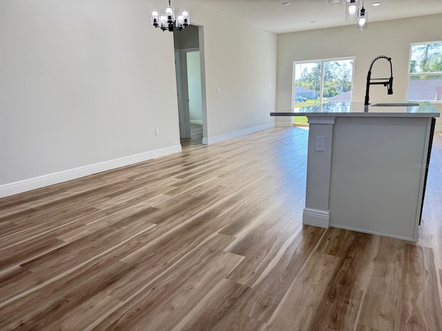 2336 SW 168th Loop, Ocala, FL 34473 - kitchen featuring a chandelier, a sink, light wood finished floors, hanging light fixtures, and baseboards