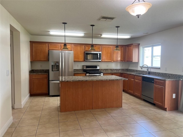 1325 Bella Coola Dr, Orlando, FL 32828 - kitchen featuring stainless steel appliances, a center island, brown cabinetry, and pendant lighting