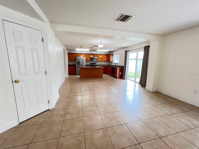 1325 Bella Coola Dr, Orlando, FL 32828 - kitchen with appliances with stainless steel finishes, dark countertops, light tile patterned floors, open floor plan, and a kitchen island