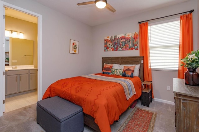 carpeted bedroom featuring ensuite bathroom, ceiling fan, and baseboards