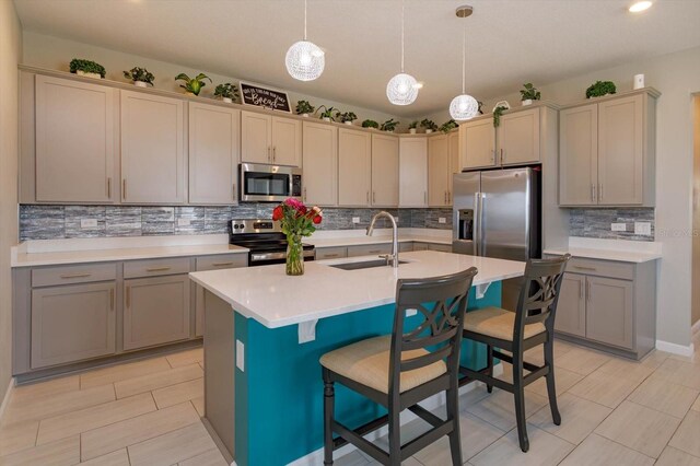 kitchen with stainless steel appliances, a sink, tasteful backsplash, a kitchen bar, and light countertops