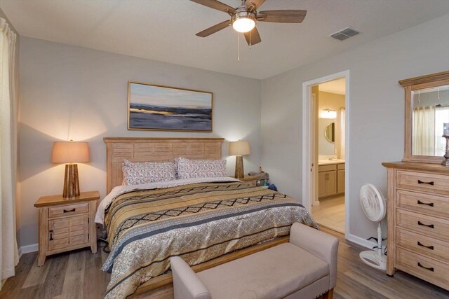 bedroom with wood finished floors, baseboards, and ensuite bath
