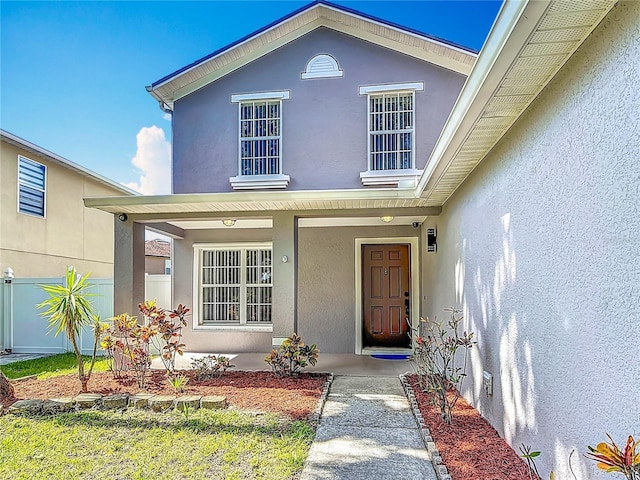 3234 Amberley Park Cir, Kissimmee, FL 34743 - entrance to property featuring covered porch, stucco siding, and fence