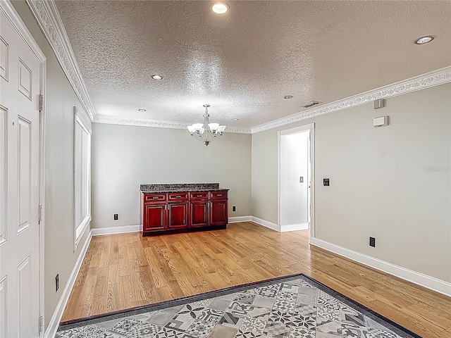 3234 Amberley Park Cir, Kissimmee, FL 34743 - unfurnished living room featuring light wood-style flooring, a chandelier, crown molding, a textured ceiling, and baseboards