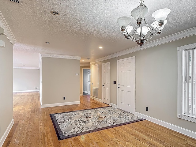 3234 Amberley Park Cir, Kissimmee, FL 34743 - foyer with a chandelier, a textured ceiling, light wood-style floors, ornamental molding, and baseboards