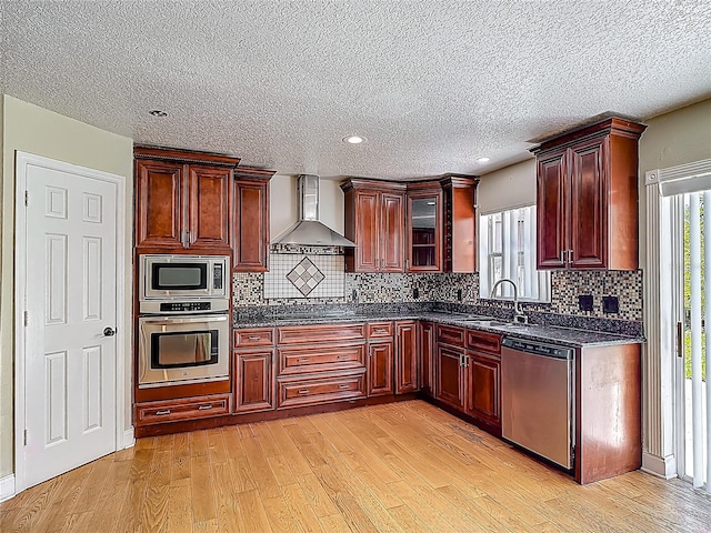 3234 Amberley Park Cir, Kissimmee, FL 34743 - kitchen featuring stainless steel appliances, wall chimney range hood, a sink, light wood-style floors, and a textured ceiling