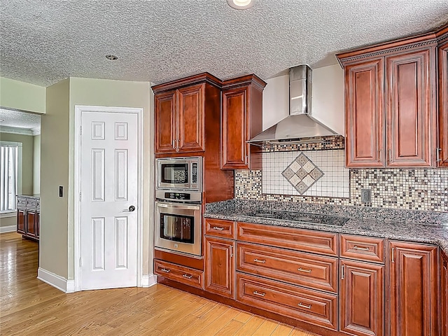 3234 Amberley Park Cir, Kissimmee, FL 34743 - kitchen with stainless steel appliances, wall chimney range hood, light wood-style floors, decorative backsplash, and a textured ceiling