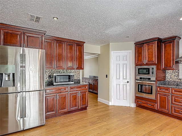 3234 Amberley Park Cir, Kissimmee, FL 34743 - kitchen with stainless steel appliances, light wood-style floors, baseboards, tasteful backsplash, and dark stone countertops